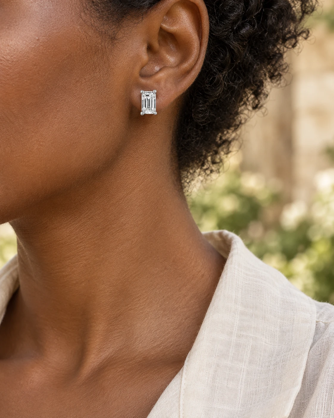 Illustrative close-up of emerald-cut diamond stud earrings, off duty styling