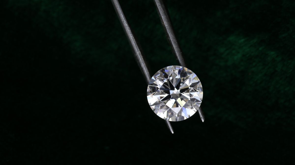 Round brilliant-cut diamond held in tweezers, close-up