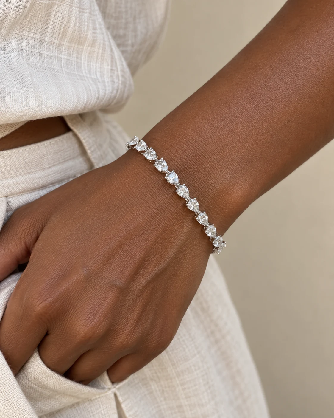 Illustrative overhead view of bracelet worn with cream linen