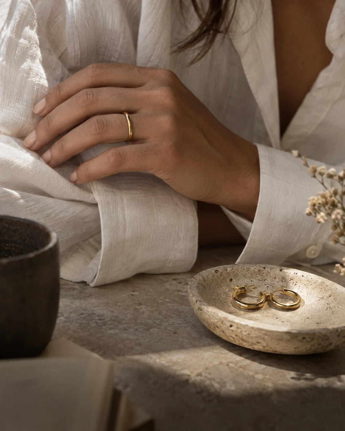 Everyday gold jewellery beside an ivory linen cuff